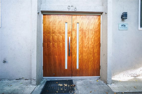 Front view of a building entrance with wooden double doors and concrete walls.