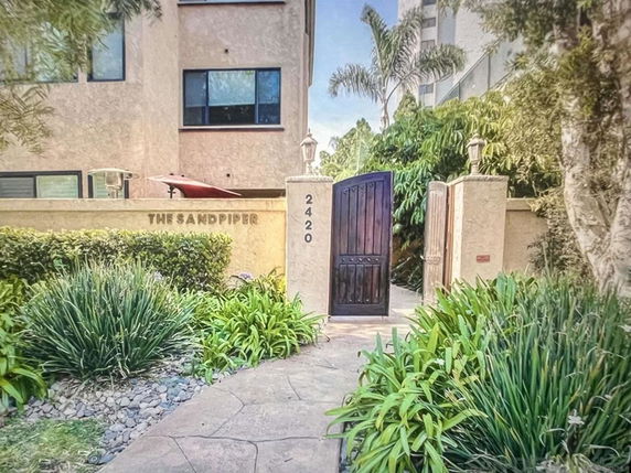 Front view of a building entrance with a gate and a sign reading 'The Sandpiper'.