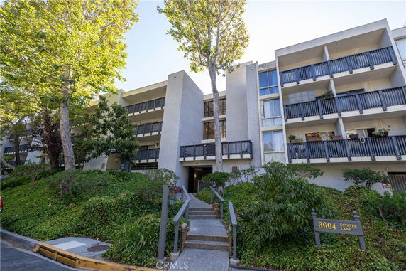 Front view of a multi-story building with multiple balconies and an entrance pathway.