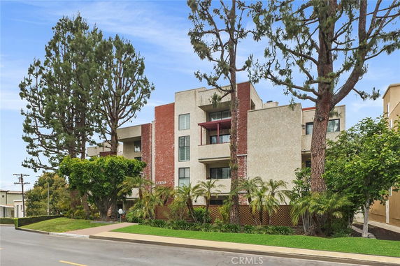 Front view of a multi-story residential building with balconies and a mix of brick and stucco exterior.