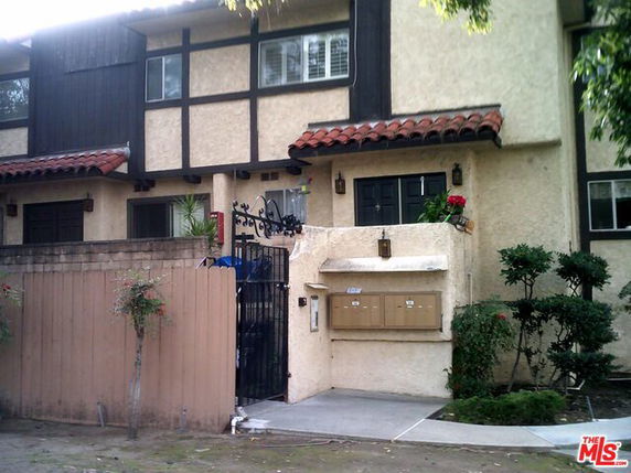 Front view of a multi-story building with a gated entry and community mailboxes.