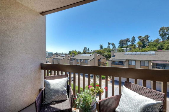 View from a balcony overlooking a residential area with solar panels on rooftops.