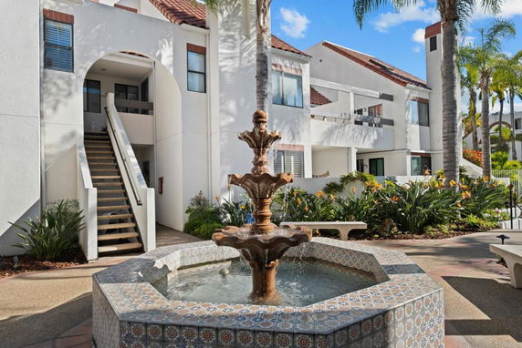 Front view of a residential building with white walls and red-tiled roof with an outdoor fountain.