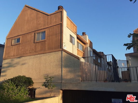 Front view of a multi-story building with a wooden facade and windows.