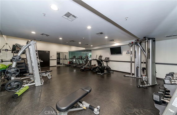 Indoor gym area with exercise equipment and weights.