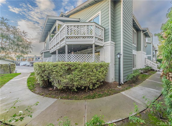 Angled view of a two-story house with balconies and green siding.