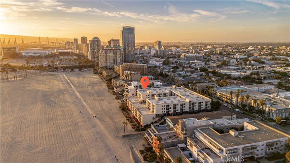 Aerial view of a cityscape with a beach in the foreground, buildings in the middle, and a city skyline in the background.
