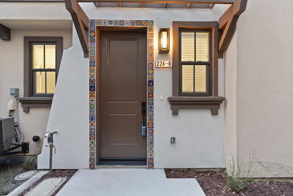 Front view of a house entrance with a brown door and decorative tiles.