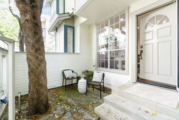 Front view of a house entrance with a door and large window, featuring a small patio area.