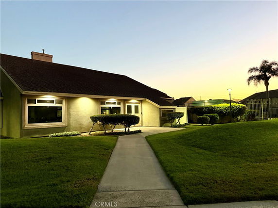 Front view of a house during sunset with a sloped roof and large windows.