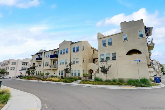 Front view of a multi-story apartment building with multiple balconies and windows.