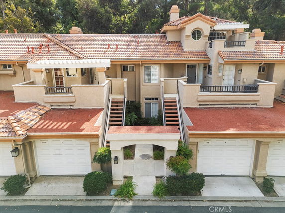 Front view of a multi-story townhouse with garages and outdoor staircases.