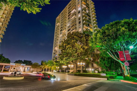 Front view of a tall residential building with multiple balconies at night.