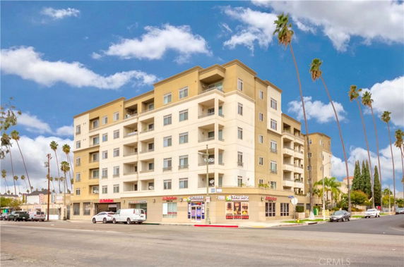 Front view of a multi-story building with balconies and ground floor shops.