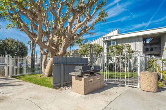 Front view of a building with a gated entrance and outdoor barbecue area.