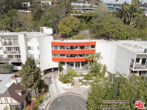 Front view of a multi-story building with a distinctive curved facade and red horizontal elements.