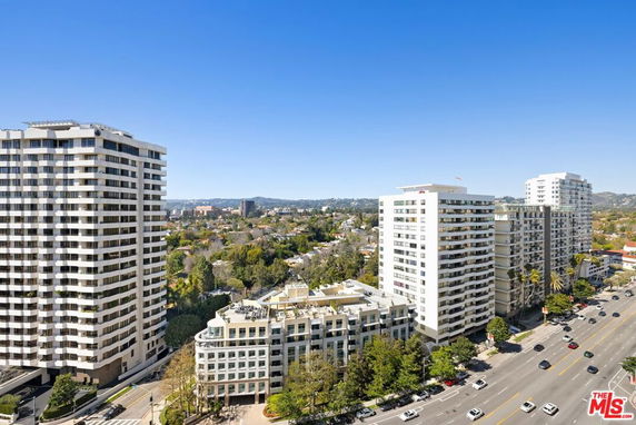 Aerial view of several multi-story residential buildings with roads and greenery in the surrounding area.