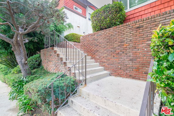 Front view of a building with a brick staircase and surrounding greenery.