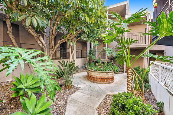 View of a landscaped courtyard area with lush greenery and plants, surrounded by building structures.