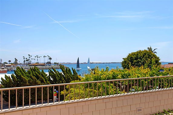 View of a waterfront with sailboats, greenery, and a distant shoreline.