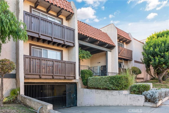 Front view of a multi-story residential building with balconies and a tiled roof.
