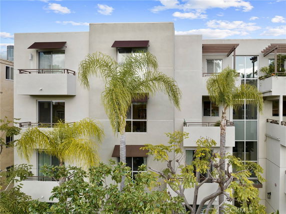 Front view of a modern multi-story building with balconies and large windows.