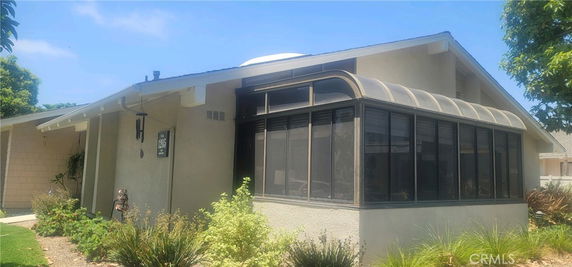 Front view of a single-story house with a screened porch and a sloped roof.