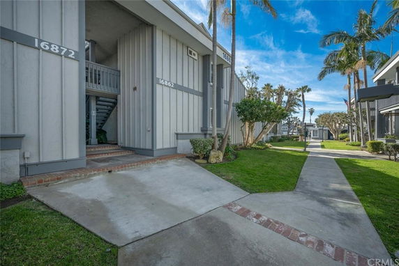 Front view of a multi-unit residential building with exterior stairs and a walkway.