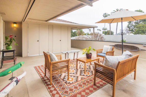 Rooftop seating area with wooden furniture and an umbrella.