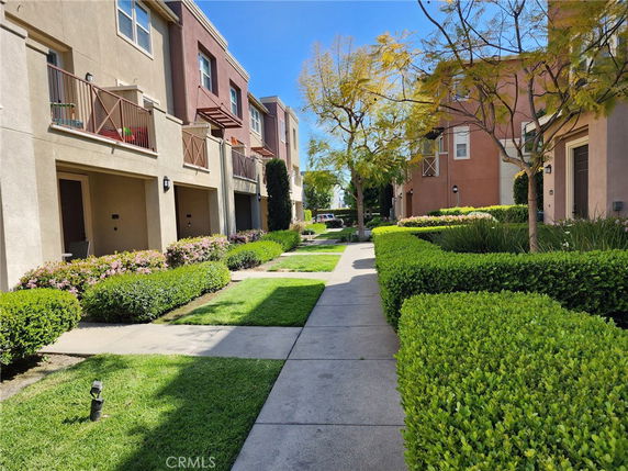 Front view of multi-story residential buildings with balconies and landscaped walkway.