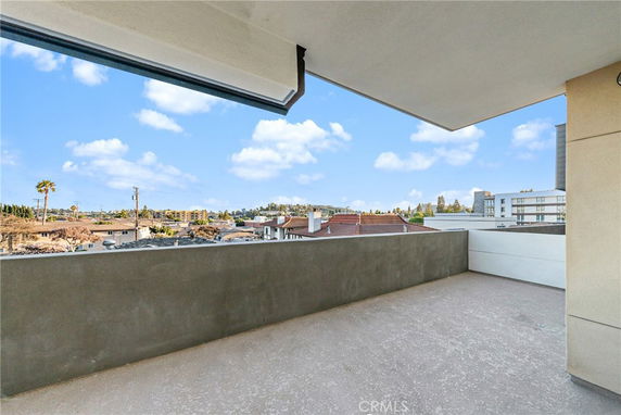 Balcony view overlooking rooftops and distant buildings.