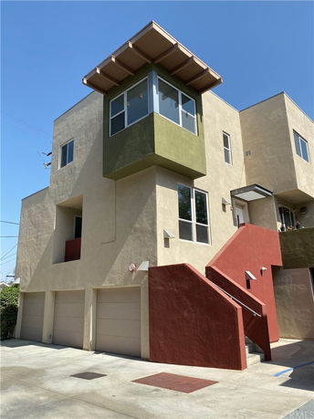 Front view of a multi-story building with a staircase and garage doors.