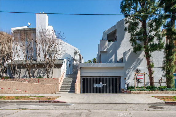 Front view of a multi-story building with a staircase and gated entrance.