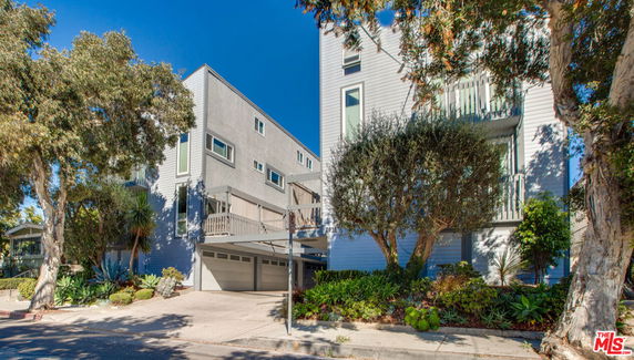 Front view of a multi-story building with garage and balconies.