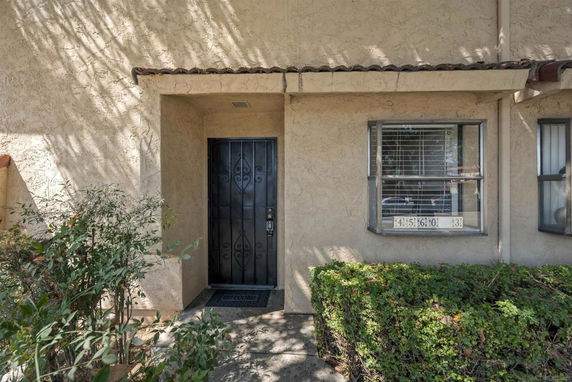 Front view of a house entrance with a black metal door and adjacent windows.