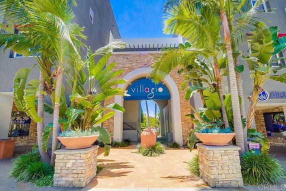 Front view of a building with an arched entrance and surrounding palm trees.