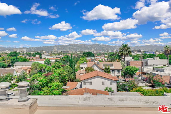 Wide angle view of a suburban area with houses, trees, and hills in the background.