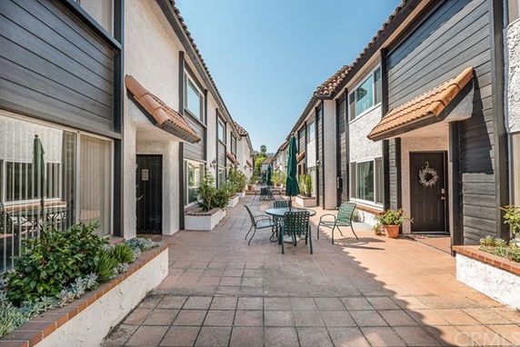 Front view of two-story townhouses with a courtyard area and outdoor seating.