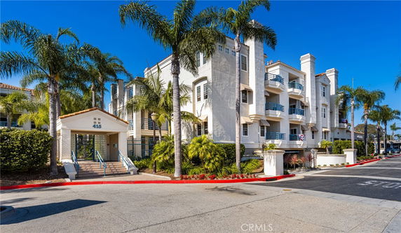 Front view of a multi-story building with balconies and palm trees.