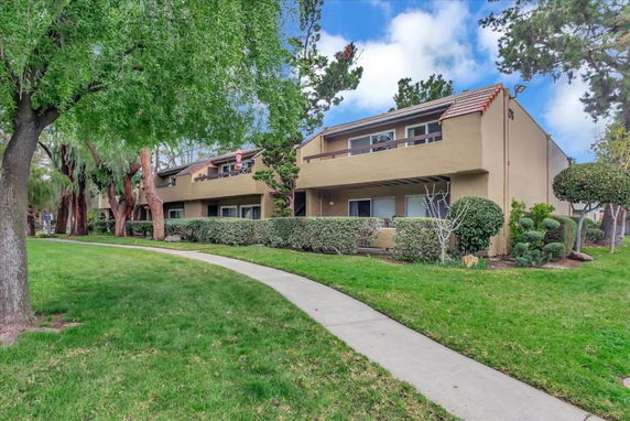 Front view of a two-story residential building with a walkway and shrubs.