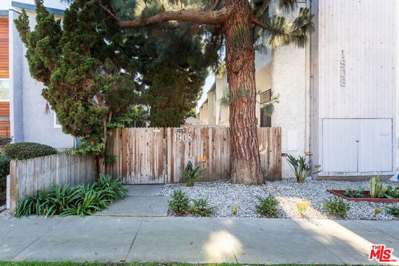Front view of a house with wooden fencing and a large tree.