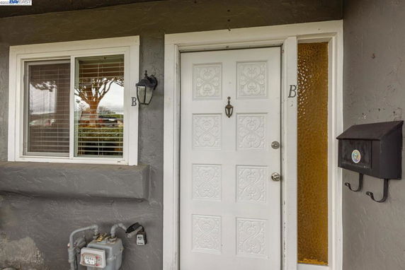 Front view of a residential entrance with a white decorative door and a window.