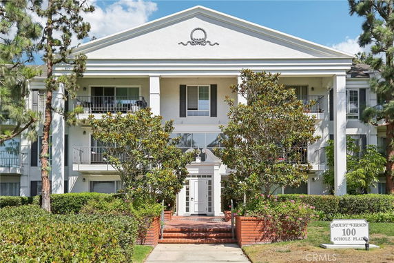 Front view of a three-story building with balconies and a central entrance.