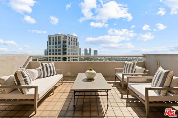 Terrace view with outdoor seating and distant city skyline.