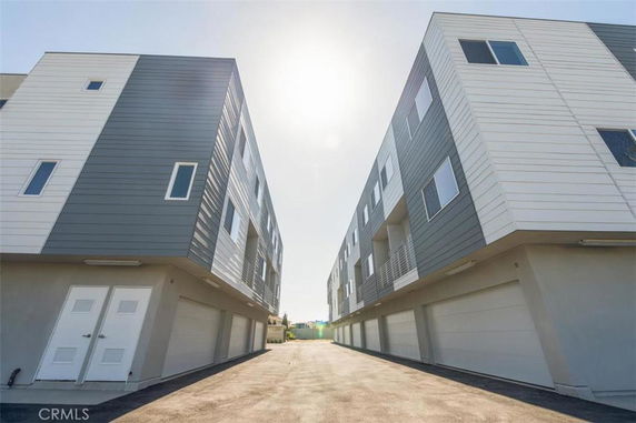 Front view of a modern multi-story building with flat roofs and multiple garage doors.