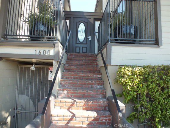 Front entrance of a building with a brick staircase and metal railings.