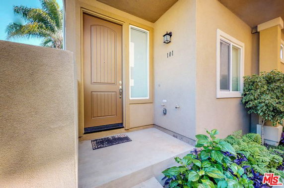Front view of a house entrance with a wooden door and small window.