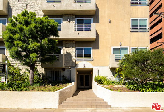 Front view of a multi-story building with balconies and a central entrance.