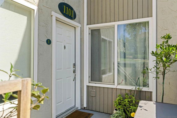 Front view of a house entrance with a white door and adjacent window.