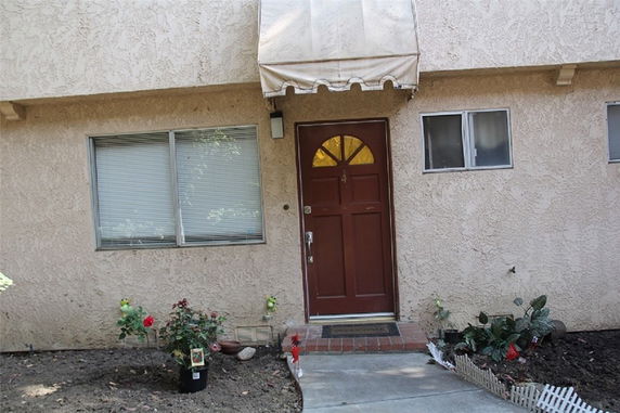 Front view of a house with a red door and window awning.